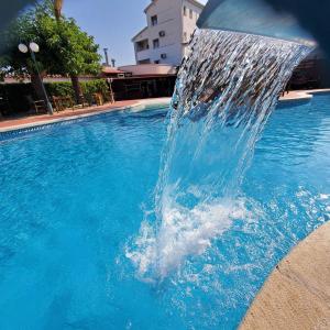 
a swimming pool with a blue water fountain at Ampuria Inn in Empuriabrava
