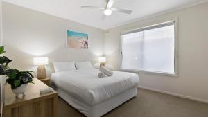 a white bedroom with a bed and a window at Sea For Miles - Scenic Coastal Retreat in Lakes Entrance +12 photos