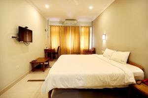 a bedroom with a large white bed and a television at KTDC Garden House in Palakkad