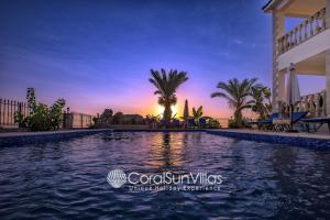een zwembad in een villa met een zonsondergang op de achtergrond bij PARADISE VILLA by Coral Sun Villas in Kato Yialia
