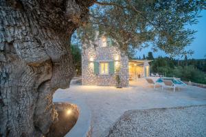 ein Steinhaus mit einem Baum und einer Terrasse in der Unterkunft VILLA AGRILI in Fiskardo