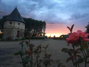 a building with a tower with a sunset in the background at Chambres dhotes a la ferme in Forest-Montiers