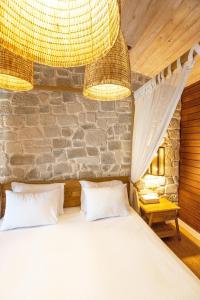 a bedroom with a large bed and a stone wall at Kimera Lounge Boutique Hotel & Spa in Cıralı