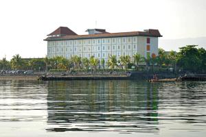 duży biały budynek obok zbiornika wodnego w obiekcie Singaraja Hotel - CHSE Certified w mieście Singaraja