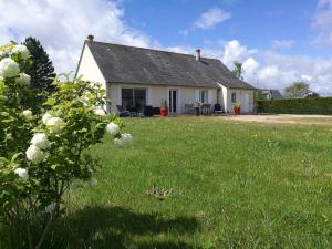 a white house with a yard with a green field at La maison des Bruyères in Orbigny