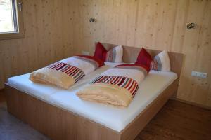 a bed with four pillows on it in a room at Haus Bianca in Schoppernau