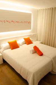 two beds with orange and white sheets in a room at Hotel Paraiso Beach by LLUM - Adults Only in Es Cana