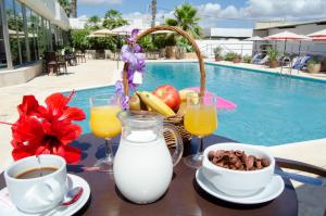 a table with a breakfast of milk and fruit next to a pool at Hotel Paraiso Beach by LLUM - Adults Only in Es Cana