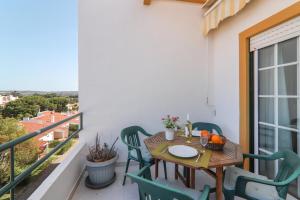 einen Balkon mit einem Holztisch und Stühlen sowie einem Fenster in der Unterkunft Casa do Algarve in Albufeira