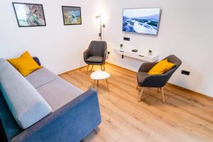 a living room with a blue couch and two chairs at Garden 13 in Tolmin