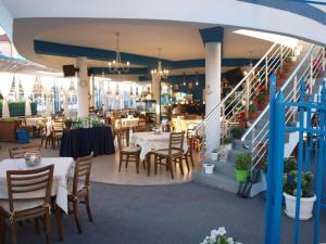 a restaurant with tables and chairs and a staircase at Семеен Хотел "Кораб Ренеса" in Ravda