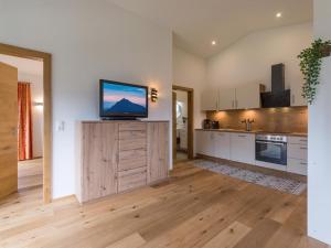 a kitchen with a flat screen tv on a wooden cabinet at Appartement Kirchner in Brixen im Thale