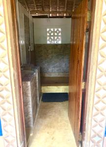 an open door of a bathroom with a sink and a window at Stilts Diani Beach in Diani Beach