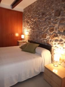 a bedroom with a bed and a stone wall at L'horitzó I in Llado