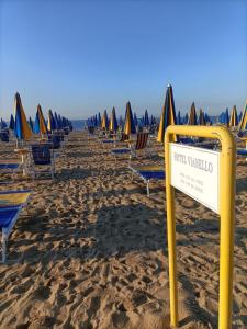 Hotel Vianello في ليدو دي يسولو: مجموعة من الكراسي والمظلات على الشاطئ