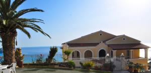 a house with a palm tree and the ocean at Apartments Maria with Pool - Agios Gordios Beach in Agios Gordios +10 photos