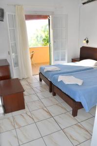 a bedroom with a bed with a blue blanket on it at Apartments Maria with Pool - Agios Gordios Beach in Agios Gordios