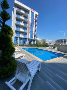 uma piscina do hotel com espreguiçadeiras e um edifício em Hotel Skyline Batumi em Batumi