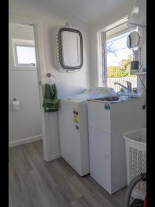 a kitchen with white cabinets and a sink and a window at Te Anau Holiday Home - Free WIFi - Free Bikes & Kayaks - Short Walk to Lake & Town - Top Views in Te Anau