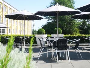 Vejle Center Hotel في فيجلي: مجموعة طاولات وكراسي مع مظلات