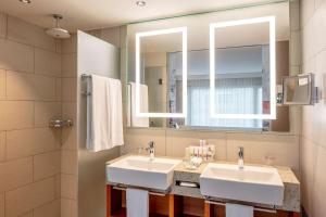 Baño con 2 lavabos y espejo en becozy Self Check-in & Pop-up Hotel, en Zúrich