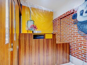 a kitchen with wooden cabinets and a brick wall at OYO 90426 Near Mall Ciputra 2 in Semarang