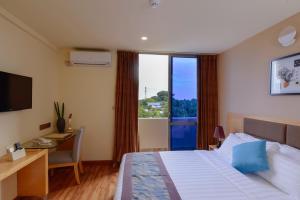 a hotel room with a bed and a desk and a window at Season Paradise in Thulusdhoo
