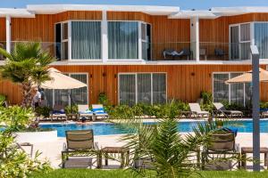 a pool with chairs and umbrellas in front of a building at Riva Hill Resort Lankaran in Lankaran