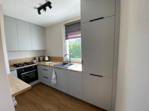 a kitchen with white cabinets and a sink at Apartament Narcyzowa in Gdynia