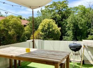 a picnic table with a grill and an umbrella at Bel appart pour 6 p, clim, parking et terrasse in Aix-en-Provence