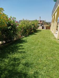 a yard with green grass and flowers next to a house at Villa Sole - Finaiti - Appartamento per turisti in Floridia
