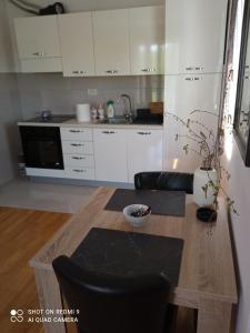 a kitchen with white cabinets and a wooden table at Apartment Anagastum in Nikšić