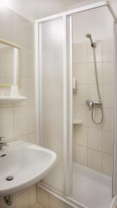 uma casa de banho branca com um chuveiro e um lavatório. em Hotel Stierer em Ramsau am Dachstein