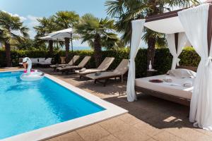 a villa with a pool and a bed and chairs at Apartments Villa Chiara Opatija in Ičići