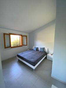 カーポ・コーダ・カヴァッロにあるCorbezzoli Apartmentの白い部屋に大型ベッド1台が備わるベッドルーム1室が備わります。