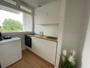 cocina blanca con fregadero y ventana en HAVEN STUUV - Zentral mit Balkon, en Bremerhaven