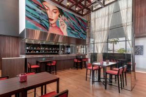 a restaurant with tables and chairs and a large painting at Hyatt Place Dubai Jumeirah in Dubai
