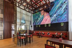 a restaurant with tables and a large painting on the wall at Hyatt Place Dubai Jumeirah in Dubai