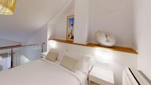 a small bedroom with a white bed and a shelf at Apartamentos La Casa El Palo in El Rompido