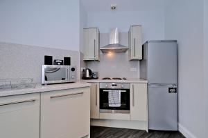 a kitchen with white cabinets and stainless steel appliances at Central Aberdeen Apartment in Aberdeen