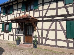 una casa con una puerta de madera y toldo en ella en Gîte Nicole, en Heidolsheim
