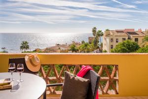 a balcony with a table and two glasses of wine at Macdonald Doña Lola Resort in La Cala de Mijas