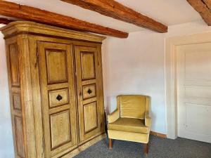 una silla amarilla en una habitación con un armario de madera en Gîte Nicole, en Heidolsheim
