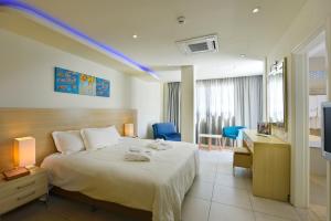 Habitación de hotel con cama, escritorio y TV. en Pernera Beach Hotel en Protaras