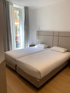 un grande letto in una camera da letto con finestra di Share Inn Appartements a Nizza
