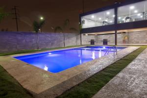 a swimming pool in front of a building at night at CHN Hotel Monterrey Aeropuerto, Trademark by Wyndham in Monterrey