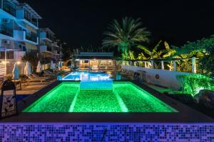 Iniohos Zante Hotel & Suites في أرغاسي: حمام سباحة في الليل مع أضواء خضراء