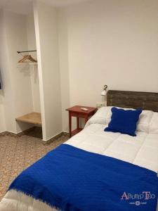 Un dormitorio con una cama azul y blanca y una mesa en Casa Rural Abuelo Teo, en Campo de Criptana