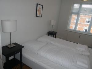 a bedroom with a white bed with two tables and a lamp at Bentzonsvej in Copenhagen