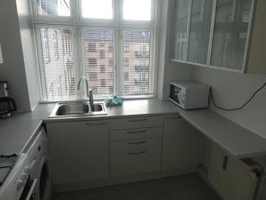a kitchen with white cabinets and a sink and two windows at Bentzonsvej in Copenhagen